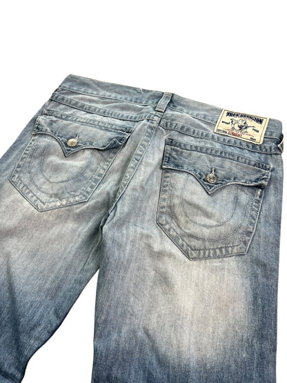 Die True Religion Straight Jeans von ZAZA resell in Größe 36 (XL) ist hellblau, hat zwei Gesäßtaschen mit Knopfverschluss, einen weißen Markenaufnäher am Bund und detaillierte Größenangaben wie Bundweite und Außenbeinlänge.