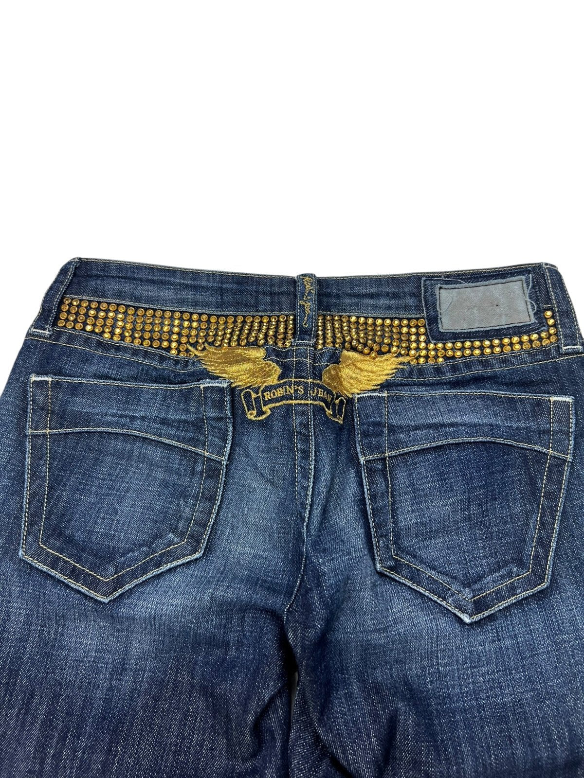 Rückansicht der Robin's Jean Low Rise Boot Jeans von ZAZA resell in blauem Denim, mit goldenem Nietenbund, goldbestickten Flügeldetails über den Taschen und einem leeren Lederaufnäher auf der rechten Seite mit der Aufschrift Größe 26 (S).