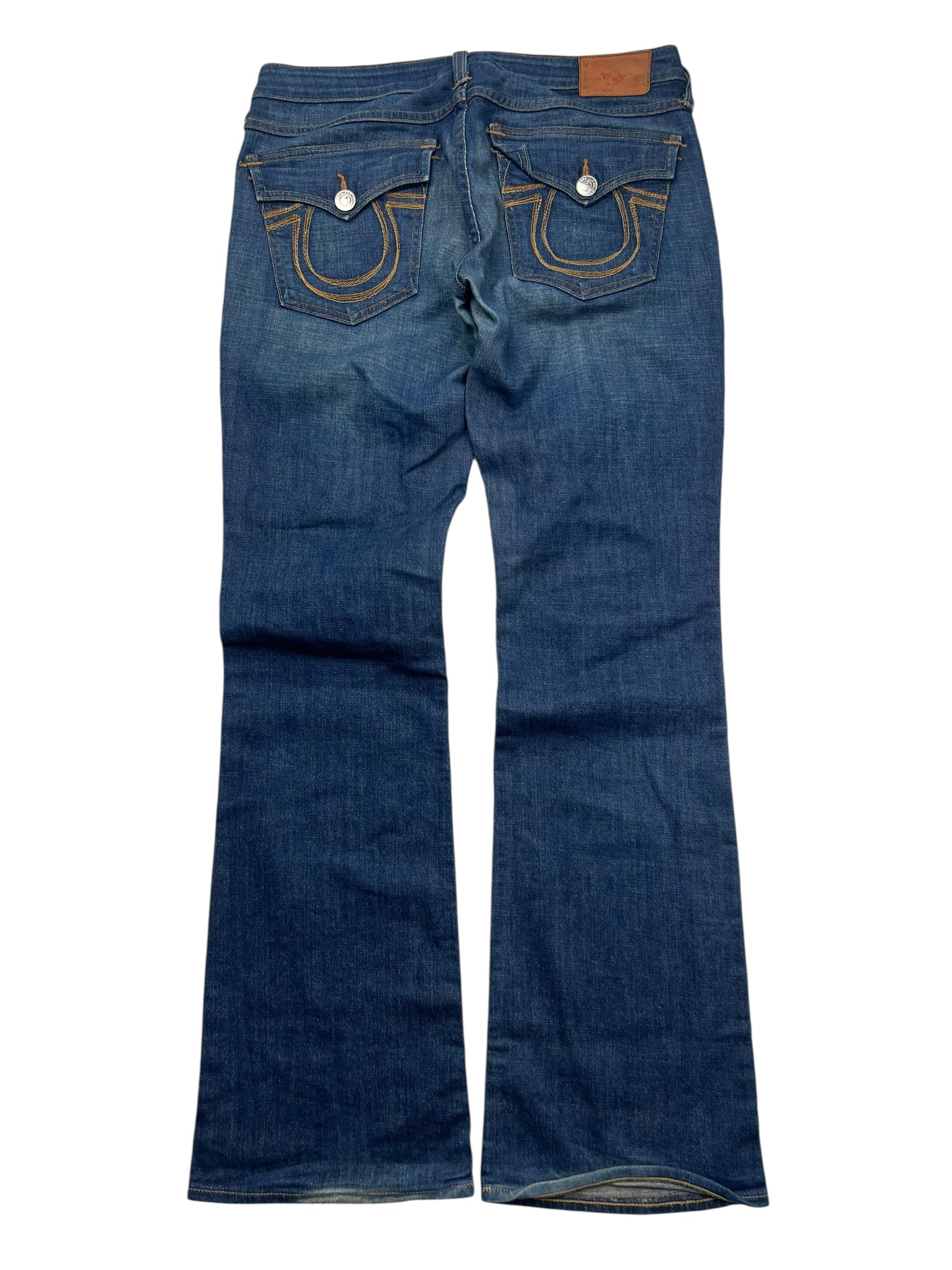 Ein Paar blaue True Religion Becky - Mid Rise Boot Jeans (Größe 30, ZAZA resell) flach gelegt zeigt Gesäßtaschen mit abgesteppten Rundungen, Knopfklappen und einen braunen Lederbundaufnäher-das ist ein seltenes Modell aus der TR Hose Kollektion.