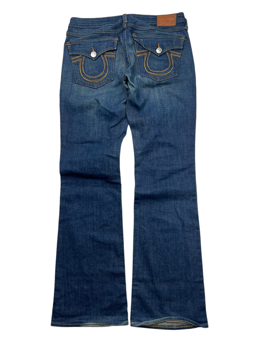 Ein Paar blaue True Religion Becky - Mid Rise Boot Jeans (Größe 30, ZAZA resell) flach gelegt zeigt Gesäßtaschen mit abgesteppten Rundungen, Knopfklappen und einen braunen Lederbundaufnäher-das ist ein seltenes Modell aus der TR Hose Kollektion.