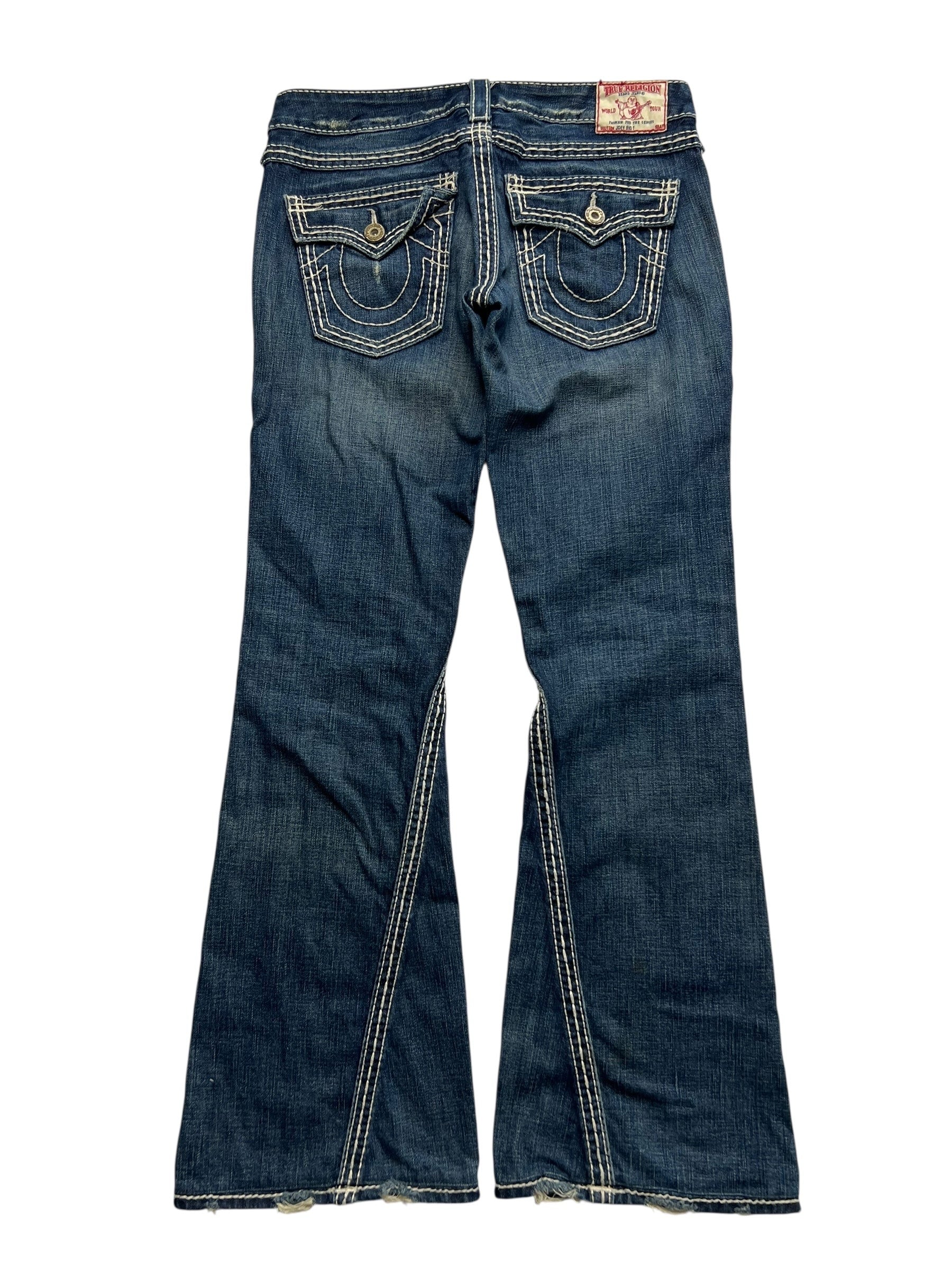 True Religion Joey Big T - Low Rise Boot Jeans von ZAZA resell in Größe 28/M, hier von hinten mit ausgestelltem Bein, weißen Kontrastnähten, dekorativen geknöpften Pattentaschen und leicht ausgefranstem Saum-ultra rare in Bundweite 40.