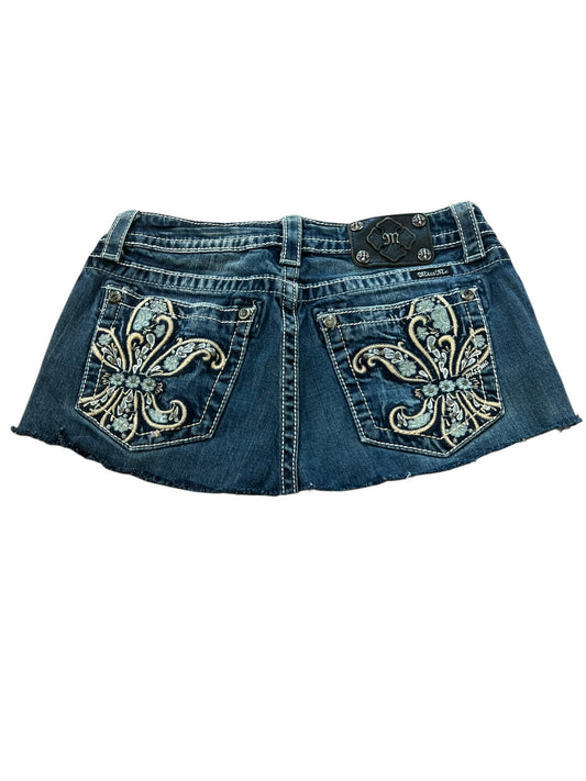 Miss Me Skirt | W28 von ZAZA Resell: dunkler Jeans-Minirock mit zwei Gesäßtaschen, kräftiger weiß-goldener Lilienstickerei, Gürtelschlaufen, Bundweite, offenem Saum und schwarzem Markenpatch am Hosenbund.