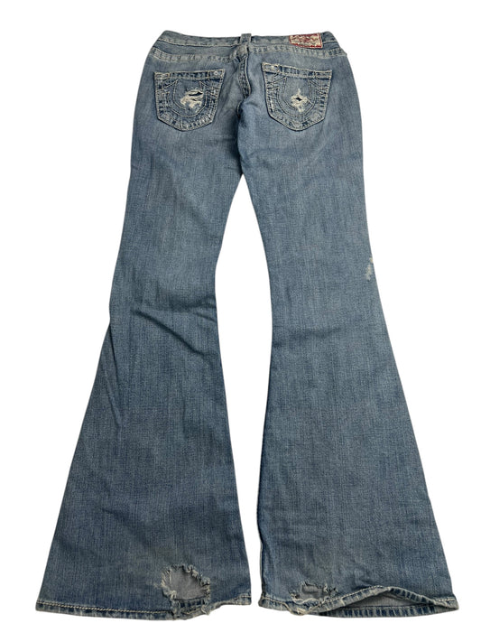 Das Modell „True Religion Jennifer Big T – Low Rise Flare“ (B26 x L31) von ZAZA Resell besteht aus blauem Denim, hat einen ausgestellten Schnitt, Gesäßtaschen und Säume im Used-Look und fällt durch seine einzigartige Außennahtlänge und die individuelle Taillenpassform auf.