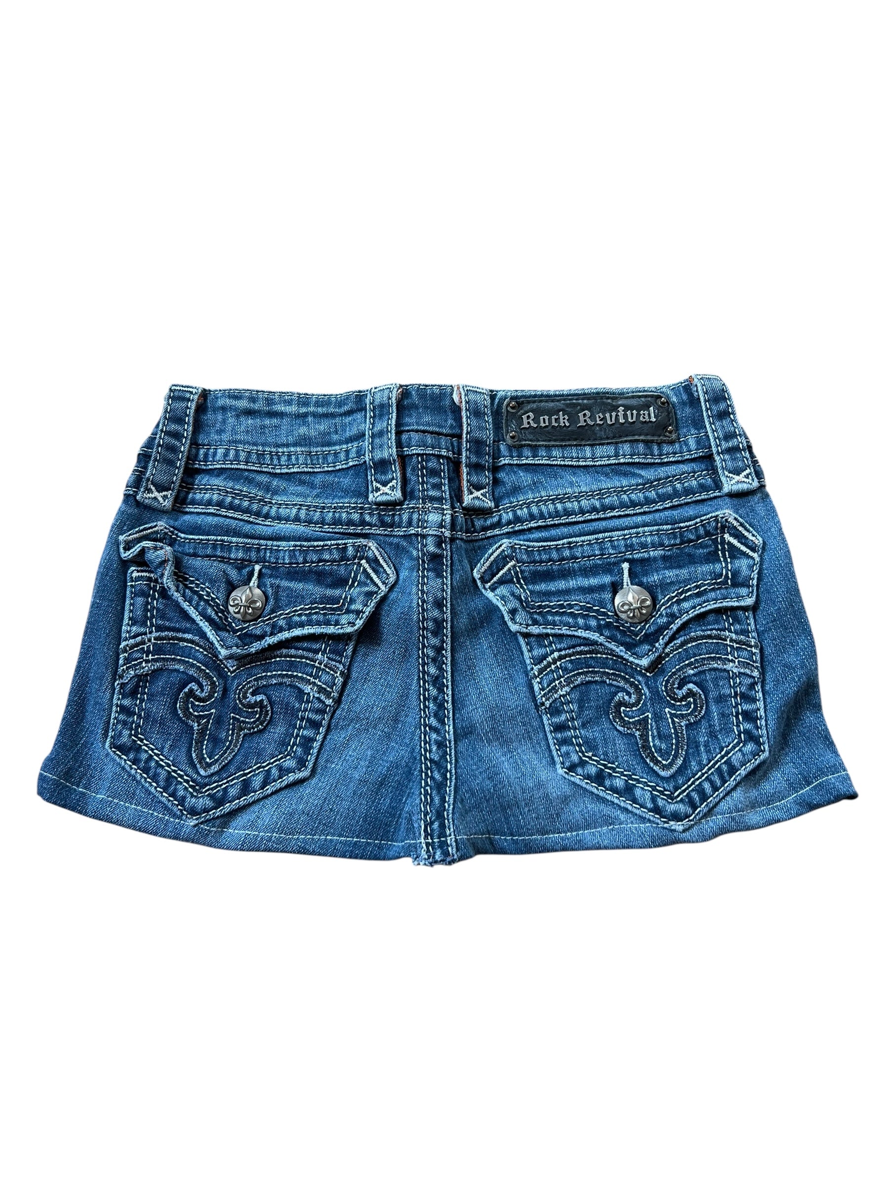 Ein blauer Jeansminirock mit Ziernähten, Pattentaschen und Metallknöpfen auf der Rückseite. Der Rock Revival Skirt | 25 (XS) der Wiederverkaufsmarke ZAZA bietet eine perfekte Passform.