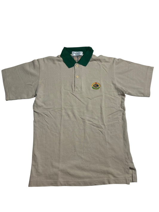 Burberry Polo Shirt | S von ZAZA resell, beige mit dunkelgrünem Kragen, kurzen Ärmeln, drei Knöpfen und gesticktem Wappen (Zustand 9/10, Labelgröße S), flach auf weißem Grund abgebildet.