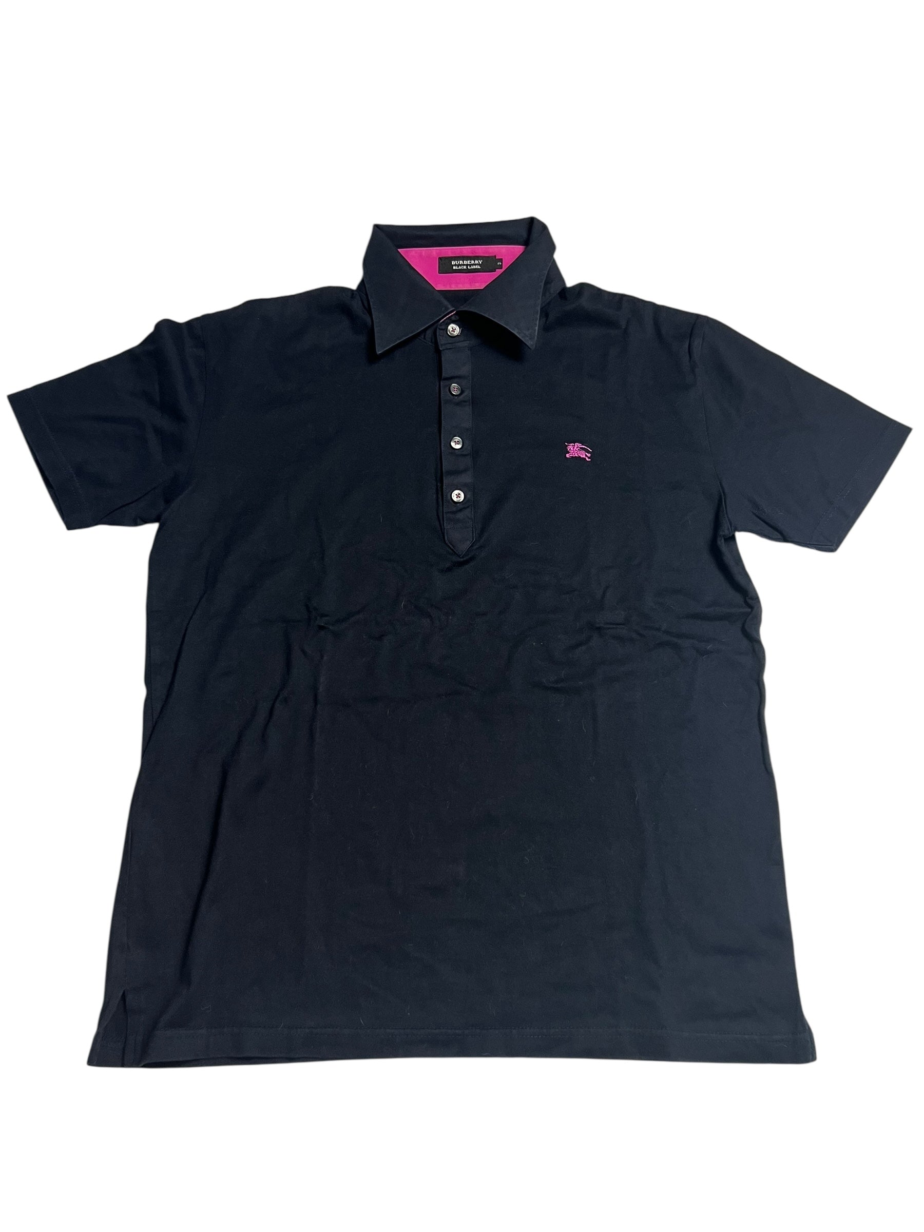 Ein schwarzes Burberry Polo Shirt (M) von ZAZA resell mit kurzen Ärmeln, Kragen, Knopfleiste und kleinem rosa Brustlogo. Größenetikett und Maße in cm stehen in der Beschreibung. Zustand: sehr gut. Flach auf einem weißen Hintergrund ausgestellt.