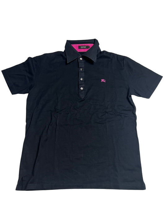 Ein schwarzes Burberry Polo Shirt (M) von ZAZA resell mit kurzen Ärmeln, Kragen, Knopfleiste und kleinem rosa Brustlogo. Größenetikett und Maße in cm stehen in der Beschreibung. Zustand: sehr gut. Flach auf einem weißen Hintergrund ausgestellt.