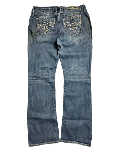 Die Rock Revival Mid Rise Boot Jeans von ZAZA resell, Größe 32 (XL), verfügt über dekorative Nähte an den Gesäßtaschen, eine leicht verblasste blaue Waschung und Bundweite 46 für eine bequeme Passform, hier von hinten.