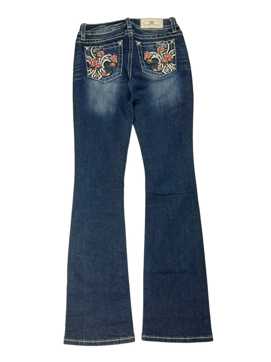 Ein Paar Miss Me Low Rise Boot Jeans in Größe 27 (S) von ZAZA resell ist von hinten abgebildet und verfügt über zwei Gesäßtaschen mit bunten Blumenstickereien.