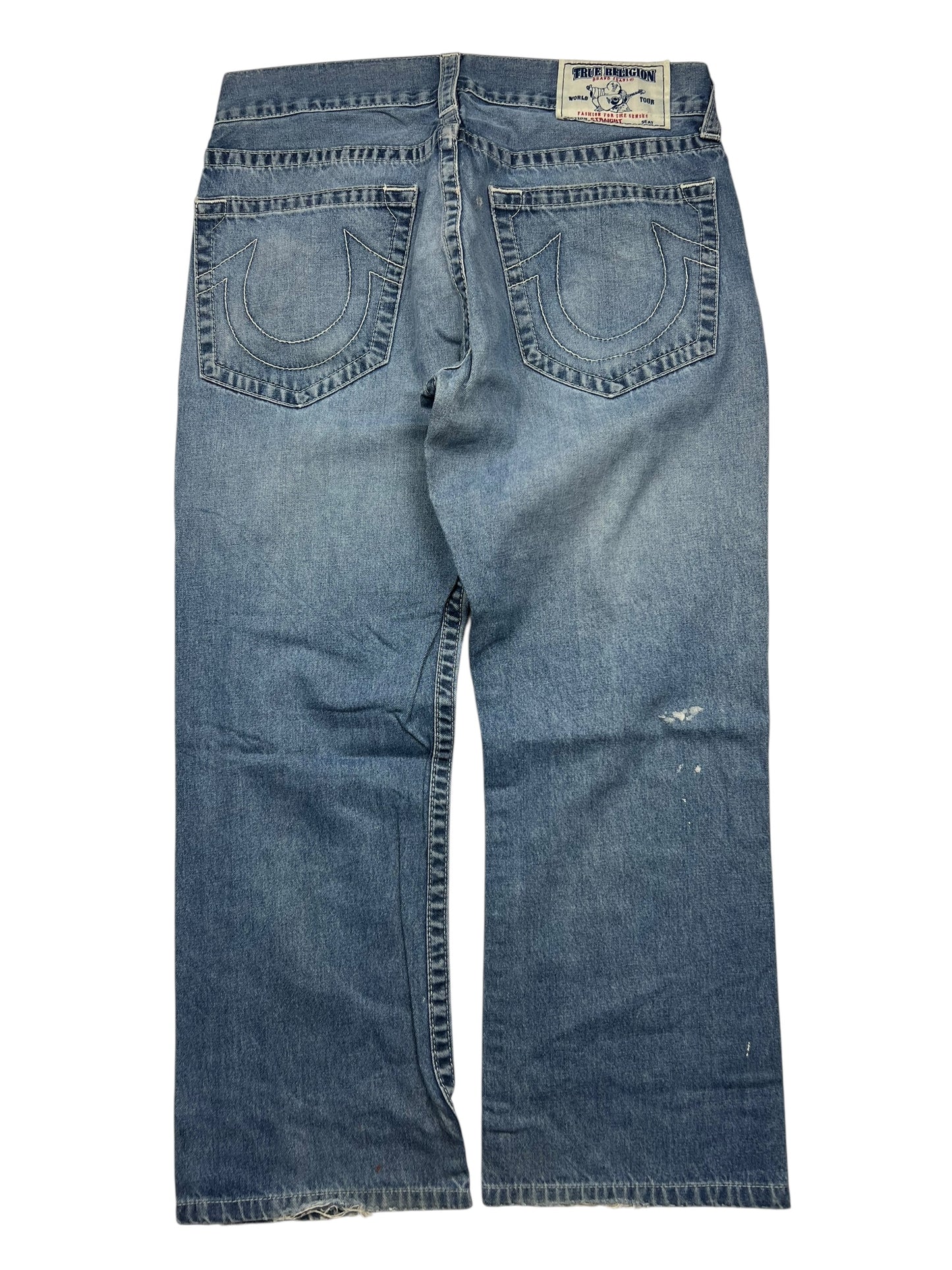 Ein Paar True Religion Straight-Jeans (Größe 34 L) von ZAZA resell, abgebildet von hinten mit zwei bestickten Hufeisentaschen, einem Markenaufnäher am Bund, einem leicht abgenutzten Look und Angaben zu Bundweite und Außenbeinlänge.