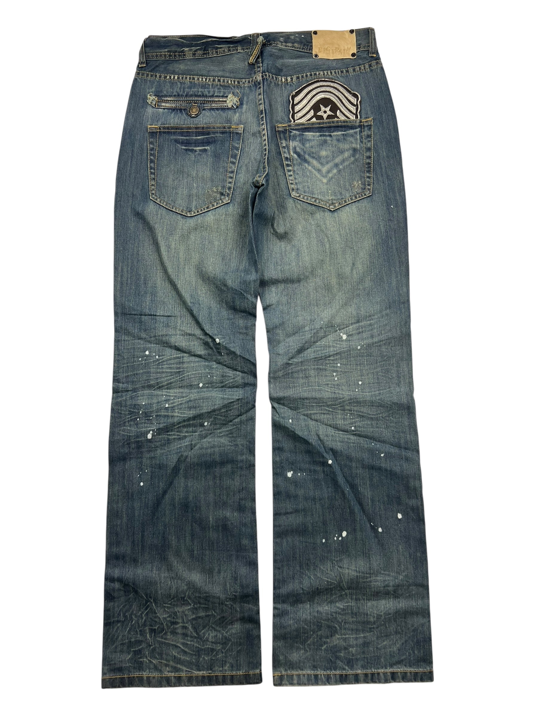 Die von hinten gezeigte ZAZA resell Big Train Boot Jeans in M/L hat verwaschene Details, Farbspritzer, einen Bundaufnäher und ein schwarz-weißes Design auf einer Tasche. Bundweite und Außenbeinlänge vervollständigen ihren unverwechselbaren Stil.