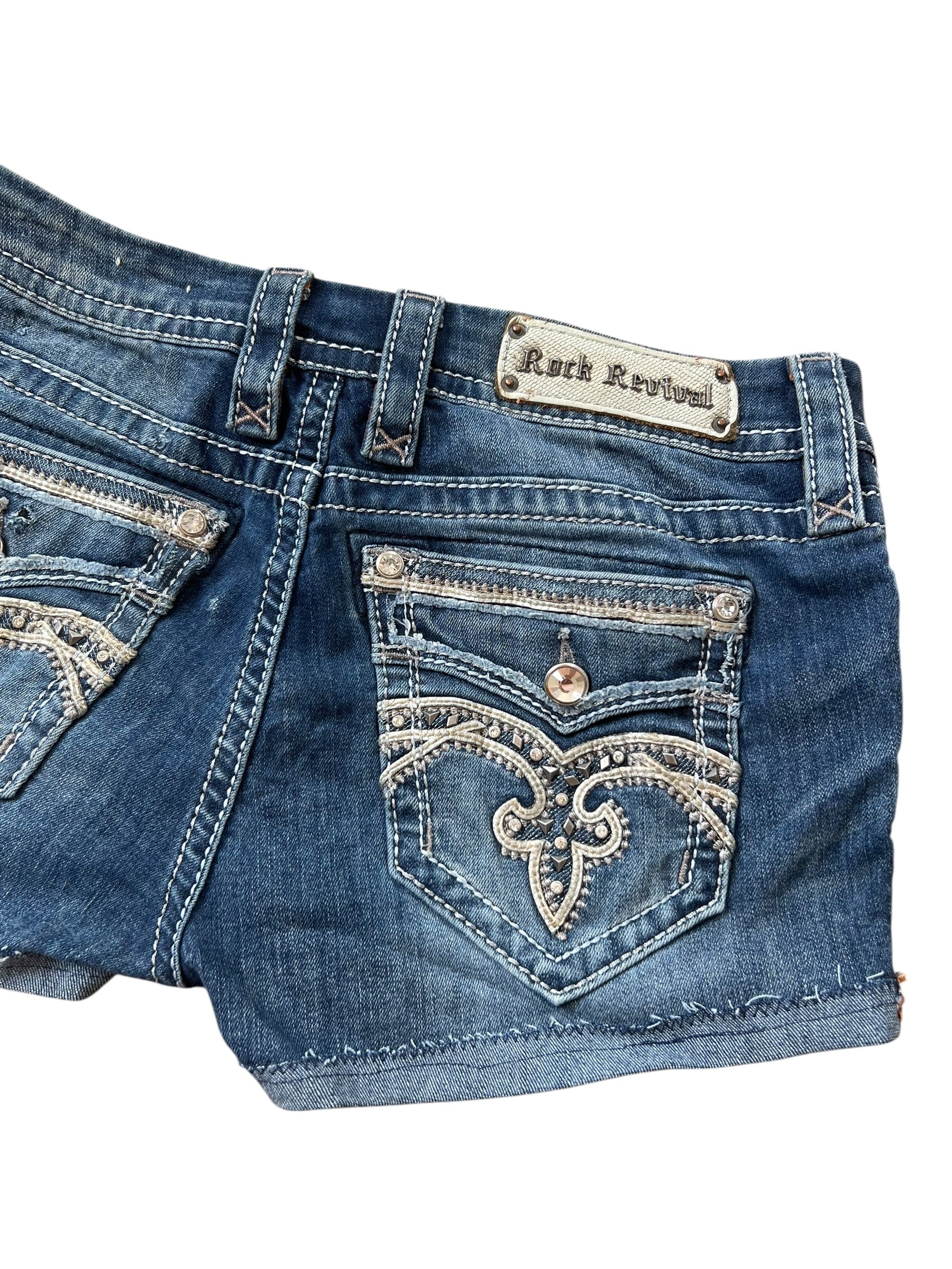 Rock Revival Shorts | 30 (M/L) von ZAZA resell: Blauer Denim mit Ziernähten, verzierter Gesäßtasche und Rock Revival Aufnäher am Bund. Größenetikett: 30, Bundweite: 41 cm.