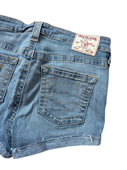 Eine Nahaufnahme der blauen True Religion High Waist Shorts (Größe 30, M) von ZAZA resell mit ausgefranstem Saum, aufgenähtem Hufeisen auf der Gesäßtasche und weißem Markenlabel am Bund.