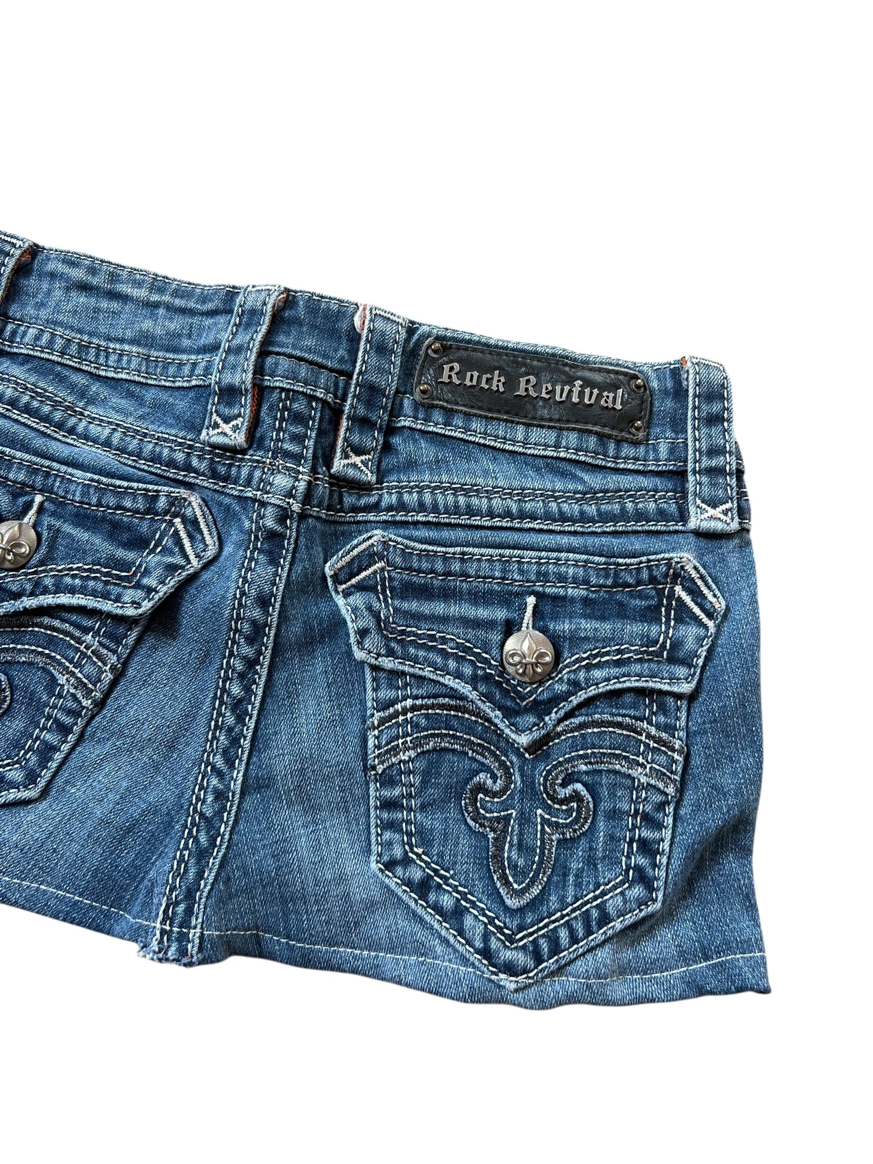 Der Rock Revival Rock in Größe 25 (XS) von ZAZA resell ist auf einem weißen Hintergrund abgebildet. Er verfügt über detaillierte Nähte, Fleur-de-Lis-Knöpfe aus Metall und das Rock Revival-Label über der rechten Tasche.