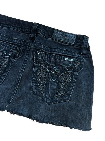 Miss Me Rock von ZAZA resell in Größe 29 (M), mit schwarzem Denim, rohem Saum, Ziernähten, Strasssteinen und einer Pattentasche hinten. Etikett und Größe sind oberhalb der Tasche sichtbar. Flach gelegt, Taille misst 39 cm auf weißem Hintergrund.