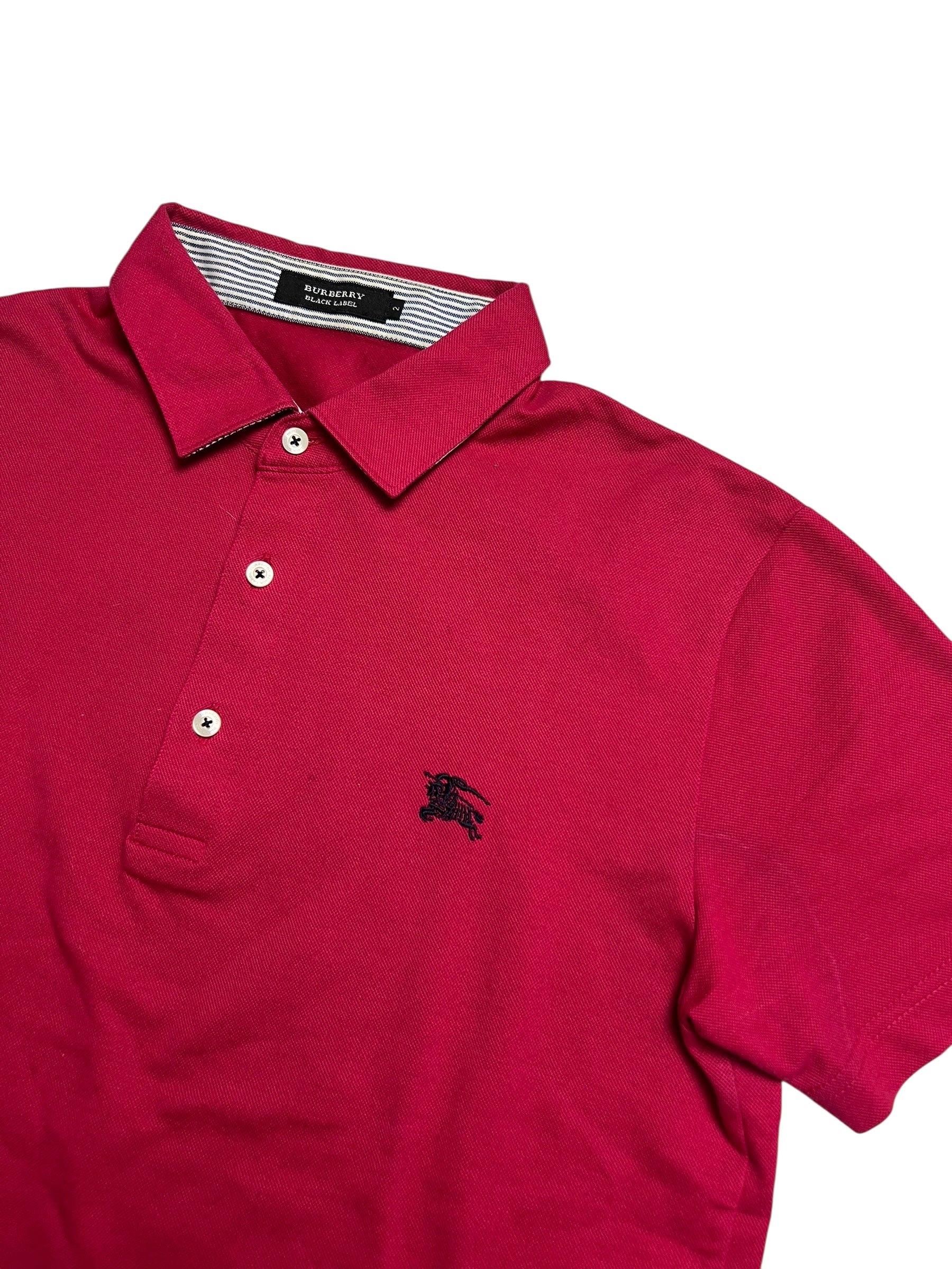 Ein rotes Burberry Polo Shirt (L) von ZAZA resell mit kurzen Ärmeln, drei weißen Knöpfen und einem schwarzen Brustlogo, flach auf weißem Grund. Zustand 8/10. Maße in Zentimetern auf Anfrage.