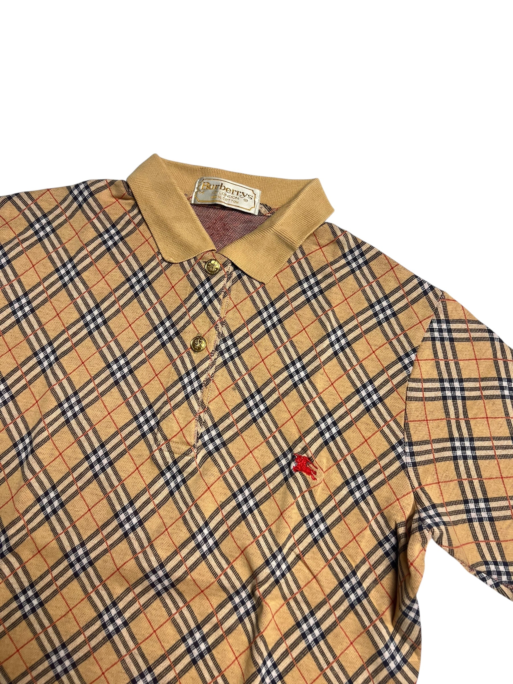 Burberry Polo Shirt | M von ZAZA wiederverkaufen: Mit beigem, schwarzem und rotem Plaid, beigem Kragen, drei Knöpfen und kleinem, rot gesticktem Brustlogo. Zustand 9 von 10. Maße auf Anfrage. Angezeigt auf weißem Hintergrund.