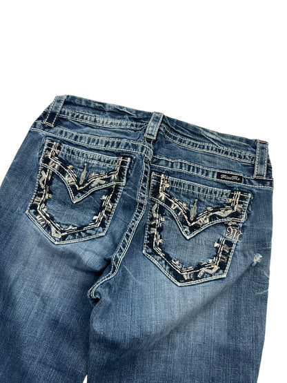 Die ZAZA resell Miss Me Mid Rise Curvy Boot Jeans in Größe 28 (M) ist aus blauem Denim mit Ziernähten, aufgestickten Gesäßtaschen und einem Schnitt für großen Hintern, der flach mit Bund und Oberschenkeln gezeigt wird.