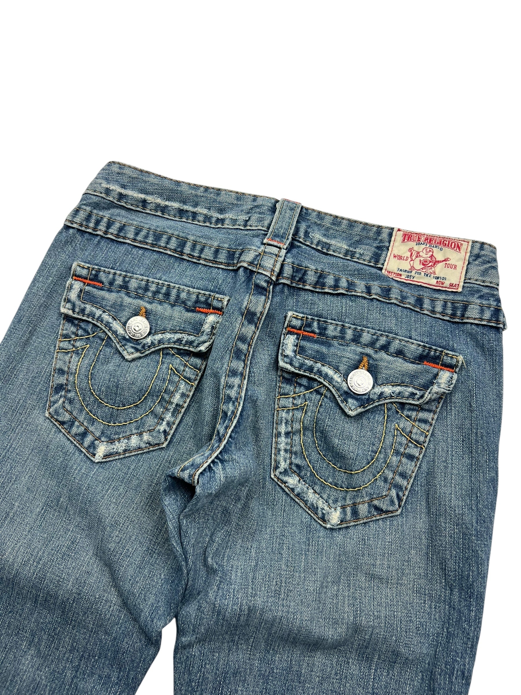 Rückansicht der True Religion Joey - Low Rise Boot Jeans von ZAZA resell in Größe 26 (S). Sie zeigt zwei Pattentaschen hinten mit weißen Nähten, silberne Knöpfe und einen Lederaufnäher mit Markenzeichen am Bund.