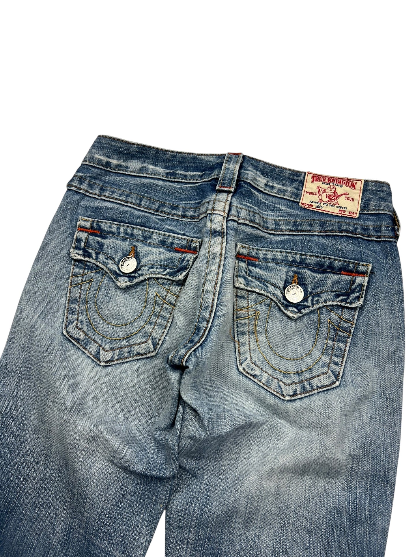 Die True Religion Joey Low Rise Boot Jeans von ZAZA resell in Größe 25 (S) hat einen hellen Denim, dekorativ aufgenähte Gesäßtaschen mit Knopfklappen, einen Markenaufnäher in der Nähe des Bundes und ein gut sichtbares Größenetikett.