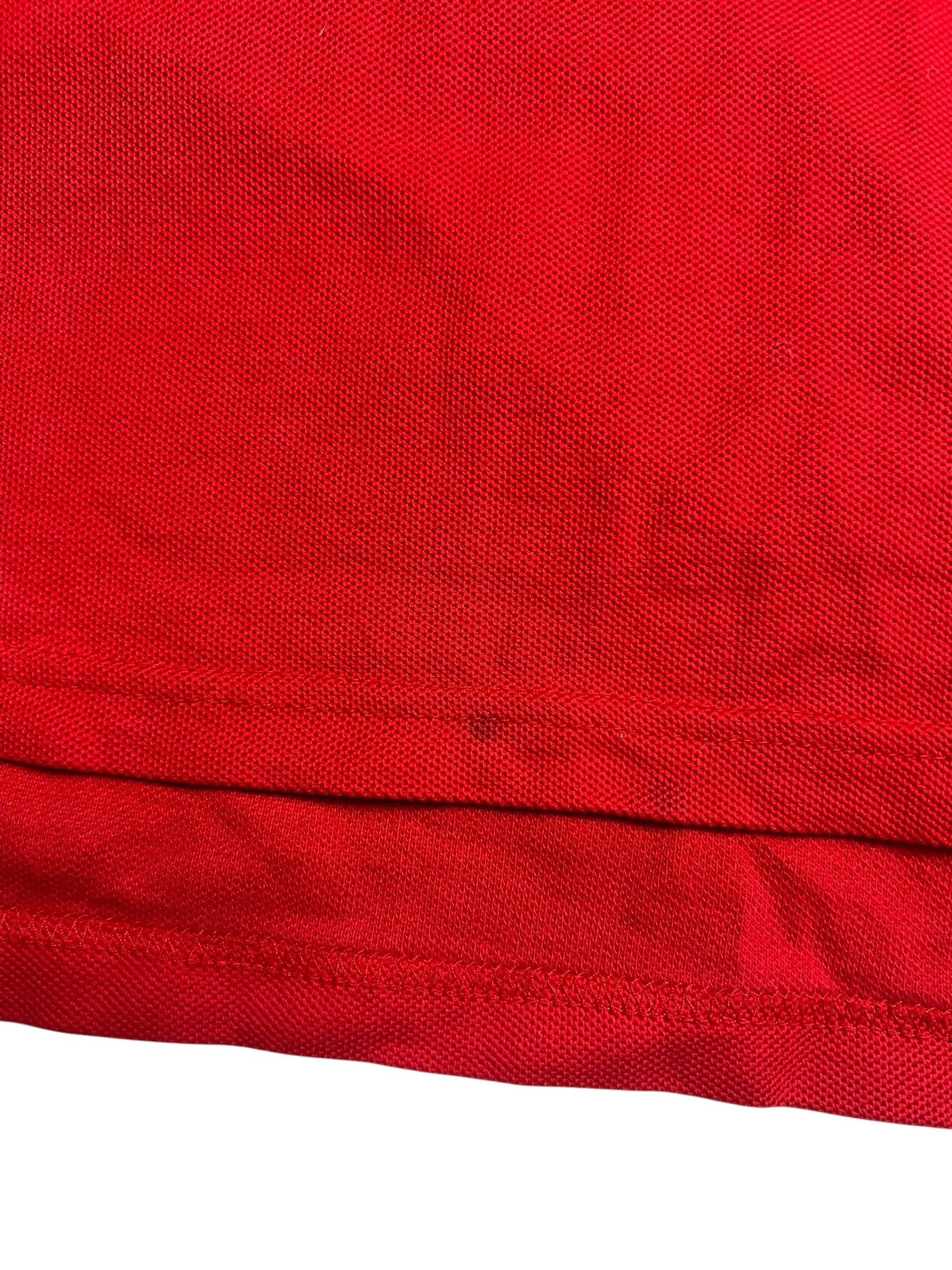 Nahaufnahme eines roten Burberry Polo Shirts (Größe M) von ZAZA resell, mit strukturiertem Netzmuster und gefaltetem Saum. Zustand: 9/10.