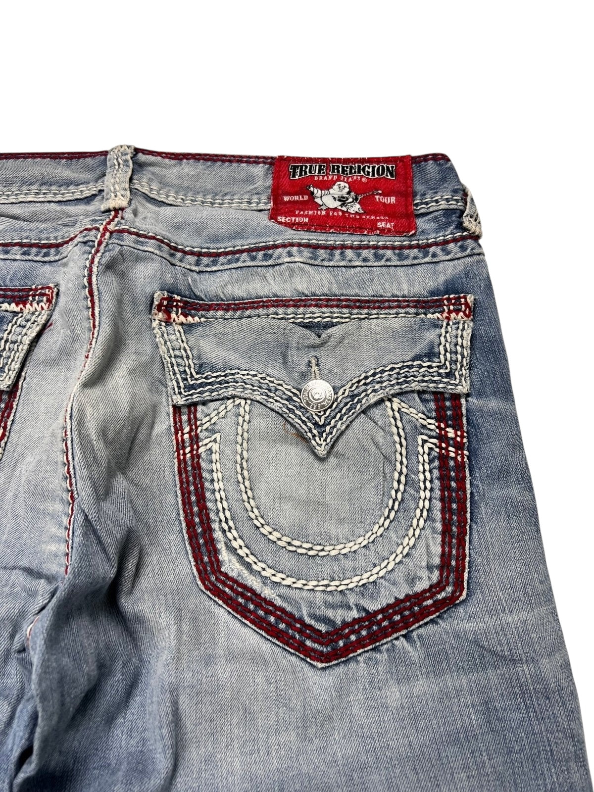 Nahaufnahme der Rückseite der True Religion Mega T Straight Jeans (34, ZAZA resell) mit detaillierten weißen und roten Nähten an der Tasche und am Bund sowie einem roten Markenetikett oben.