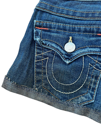 Eine Nahaufnahme der True Religion Shorts | 23 (XS) von ZAZA resell zeigt eine Gesäßtasche aus blauem Denim mit weißen und gelben Nähten, einen silbernen Knopf, rote Akzente am Bund und ein geschwungenes Design für einen klassischen Cowboy-Stil.