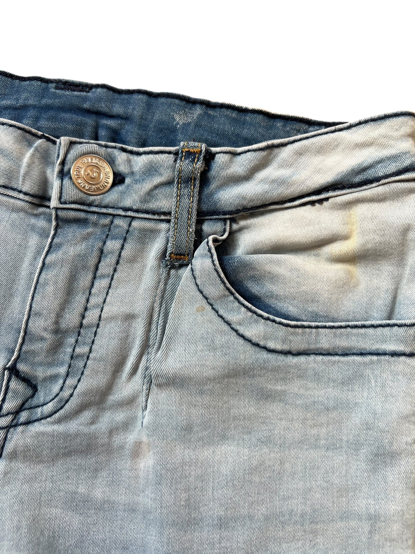 Nahaufnahme des Bundes und der Vordertasche der True Religion Shorts | S von ZAZA resell, mit Metallknopf, Gürtelschlaufe, genähten Details und einem verblichenen gelblichen Fleck in der Nähe der Tasche für einen einzigartigen Touch.