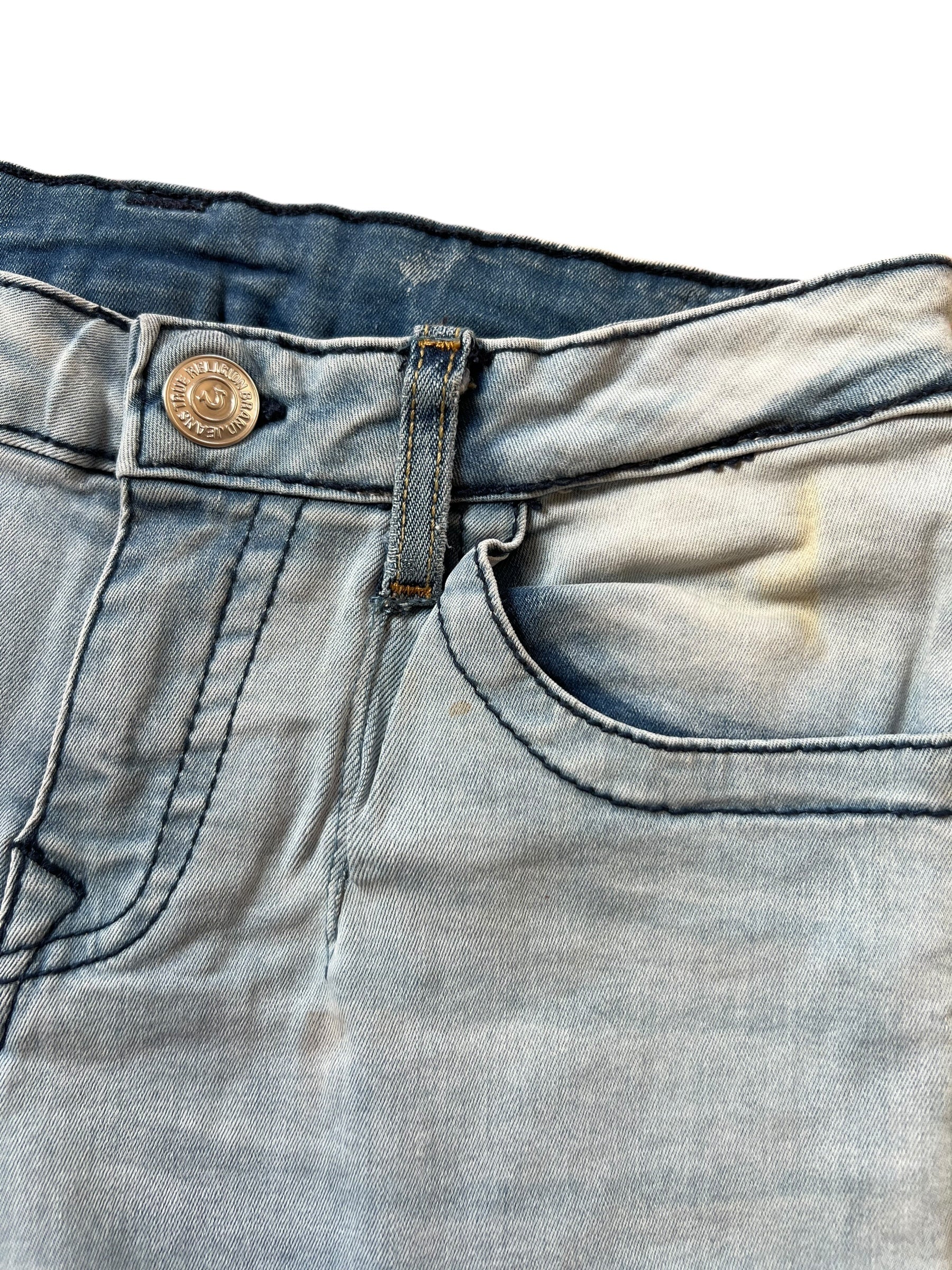 Nahaufnahme des Bundes und der Vordertasche der True Religion Shorts | S von ZAZA resell, mit Metallknopf, Gürtelschlaufe, genähten Details und einem verblichenen gelblichen Fleck in der Nähe der Tasche für einen einzigartigen Touch.