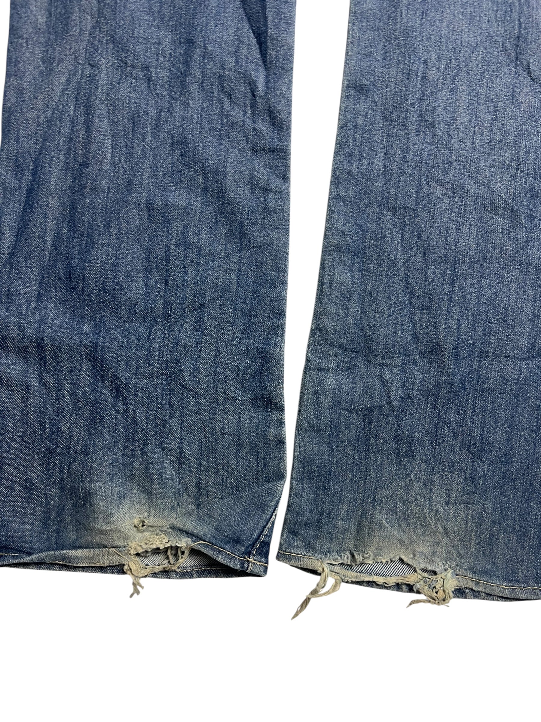 Eine Nahaufnahme der Apple Bottoms Mid Rise Boot Jeans von ZAZA resell, die hochwertiges Material mit ausgefransten, abgenutzten Säumen, losen Fäden und leichten Randverfärbungen vor einem weißen Hintergrund zeigt.