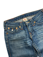 Eine Nahaufnahme einer blauen Denim-Jeans, orangefarbene Nähte, ein Knopf vorne und eine kleine Tasche. Der Bund zeigt ein Labelgröße-Tag mit einem Hufeisen-Logo und "True" aus der True Religion Billy - Low Rise Straight | 26 (S/M) von ZAZA resell.