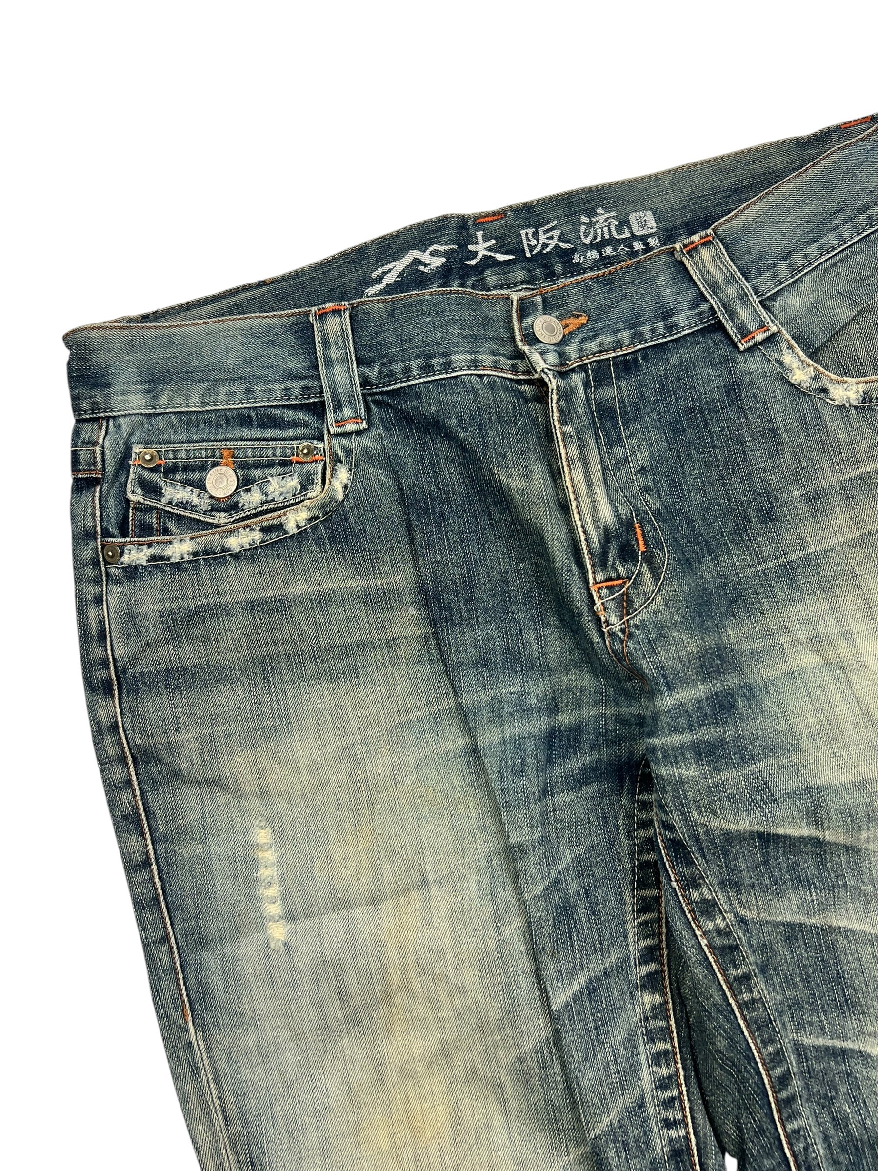 Die Big Train Boot | L von ZAZA resell sind blaue Distressed-Jeans mit verblichenen Details, einer kleinen Vordertasche, japanischem Text auf dem Innenbund und detaillierter Bundweite für Komfort.