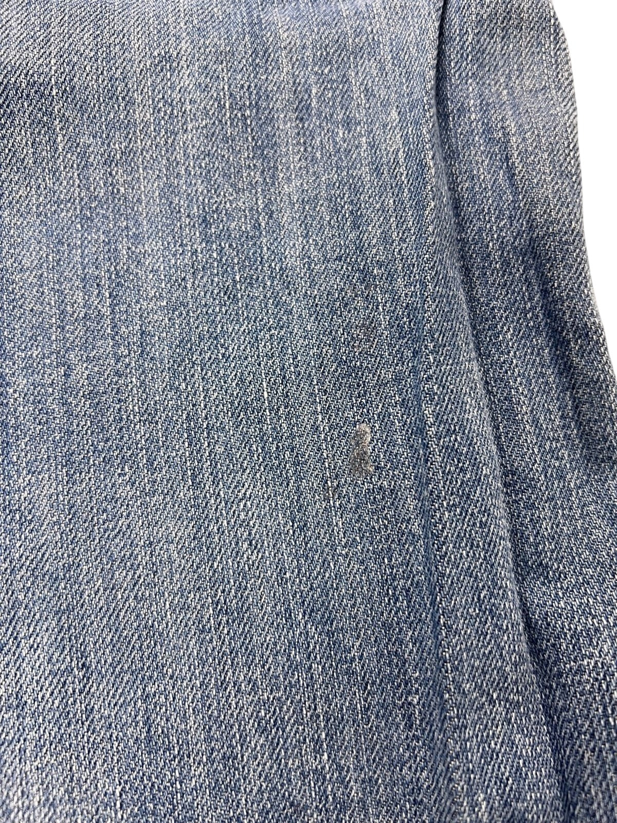 Nahaufnahme des blauen Denim-Stoffes der von ZAZA wiederverkauften True Religion Mega T Straight | 34 (M), die die Webart, die Textur und einen schwachen Abnutzungsfleck zeigt - ideal für alle, die eine genaue Bundweite oder Labelgröße 34 suchen.