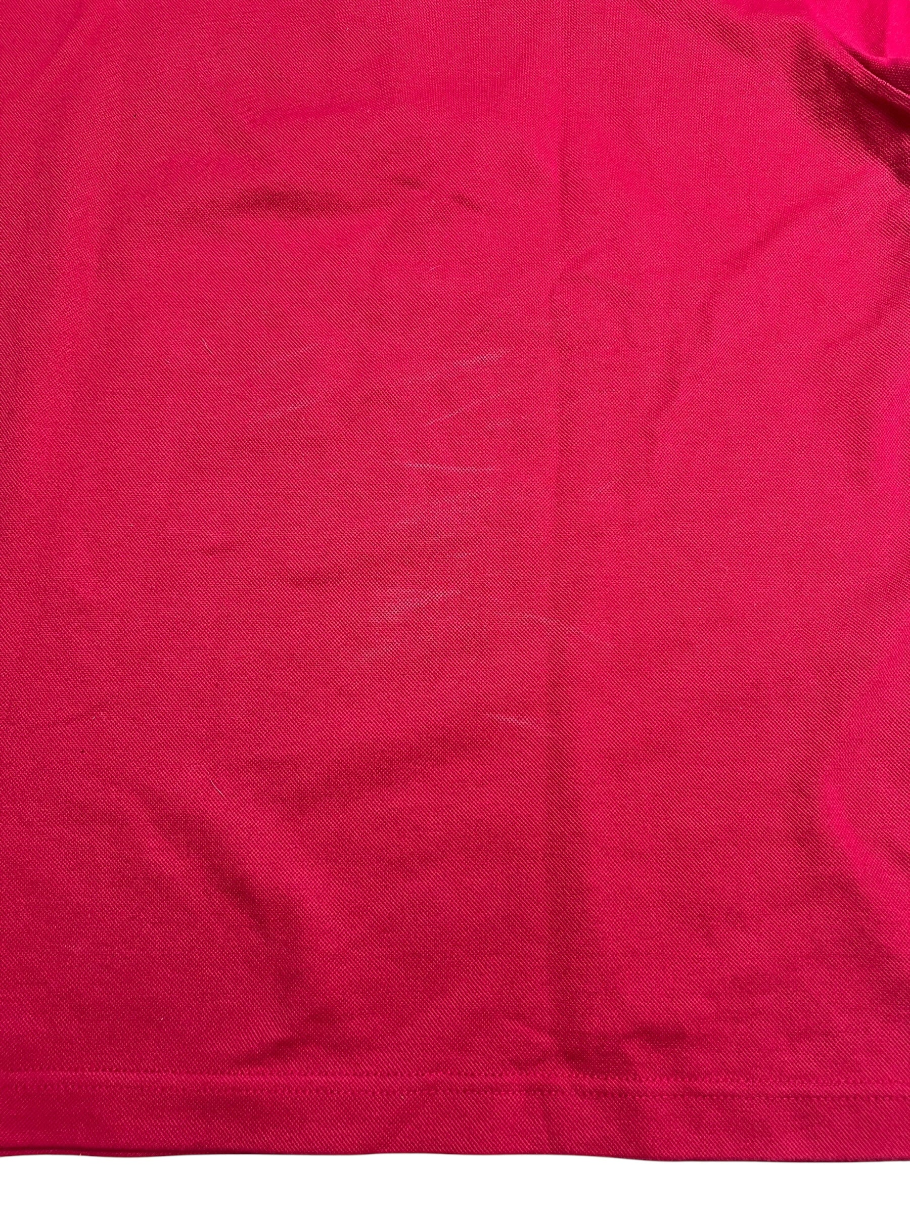 Eine Nahaufnahme eines Burberry Polo Shirts (L) von ZAZA resell zeigt roten Stoff mit schwachen weißen Kratzspuren und Falten; Zustand: 8/10.