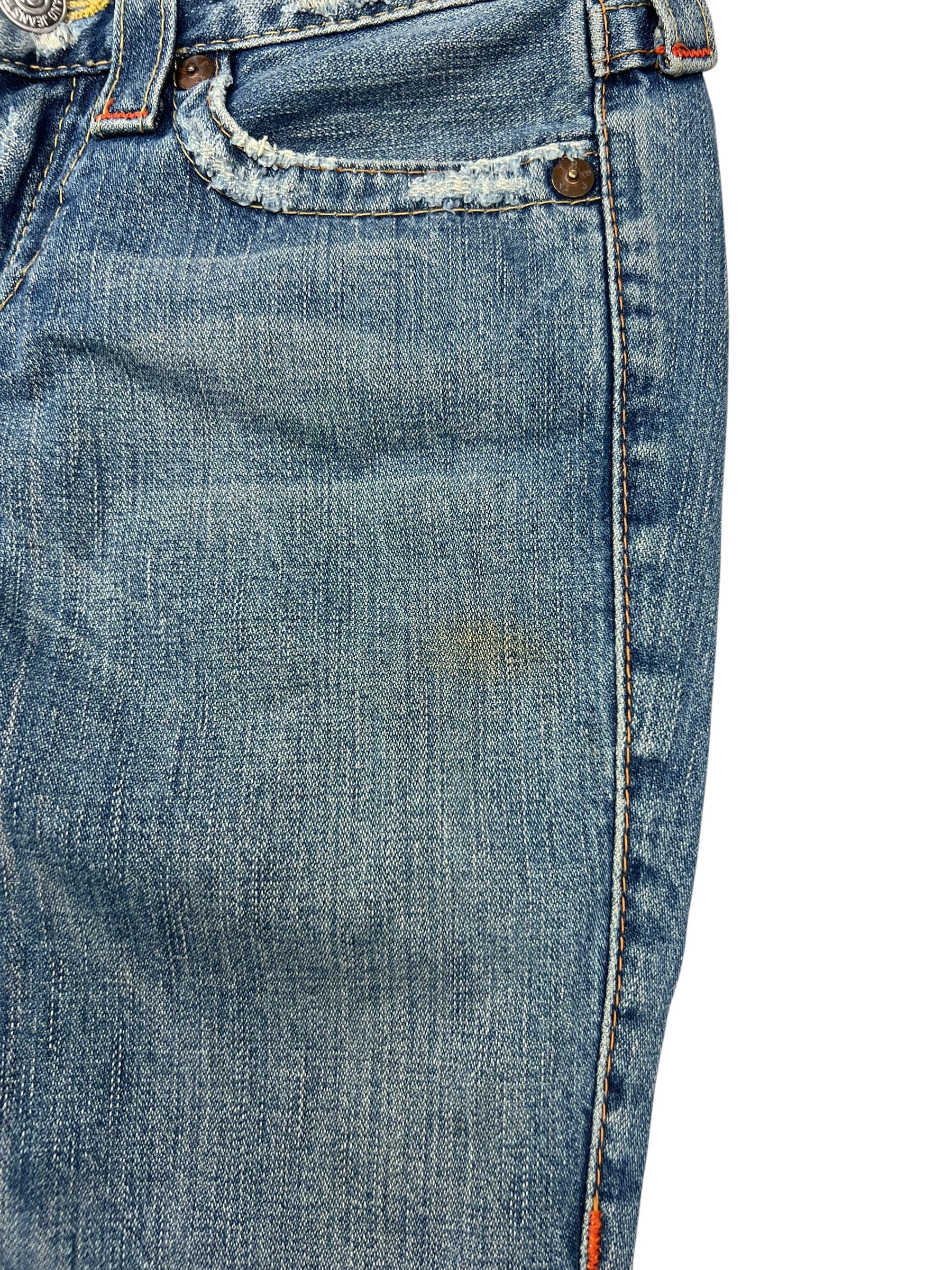 Nahaufnahme der True Religion Joey - Low Rise Boot Jeans (26/S) von ZAZA resell, mit einem kleinen braunen Fleck in der Nähe der Tasche, ausgefranstem Rand und sichtbarer Textur. Subtile Fading Highlights Etikett Größe und Bund Details für fit Referenz.
