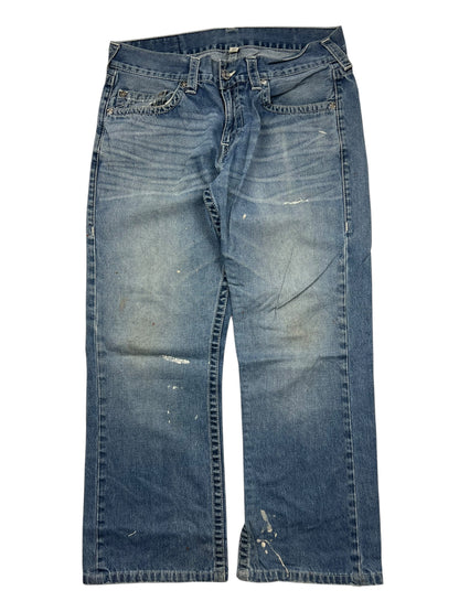 ZAZA verkauft True Religion Straight Jeans, Größe 34 (L), mit sichtbaren Ausbleichungen, Farbflecken und Knitterfalten. Das getragene blaue Paar ist flach auf einem weißen Hintergrund gelegt; Etikettengröße und Bundweite sind als Referenz gezeigt.