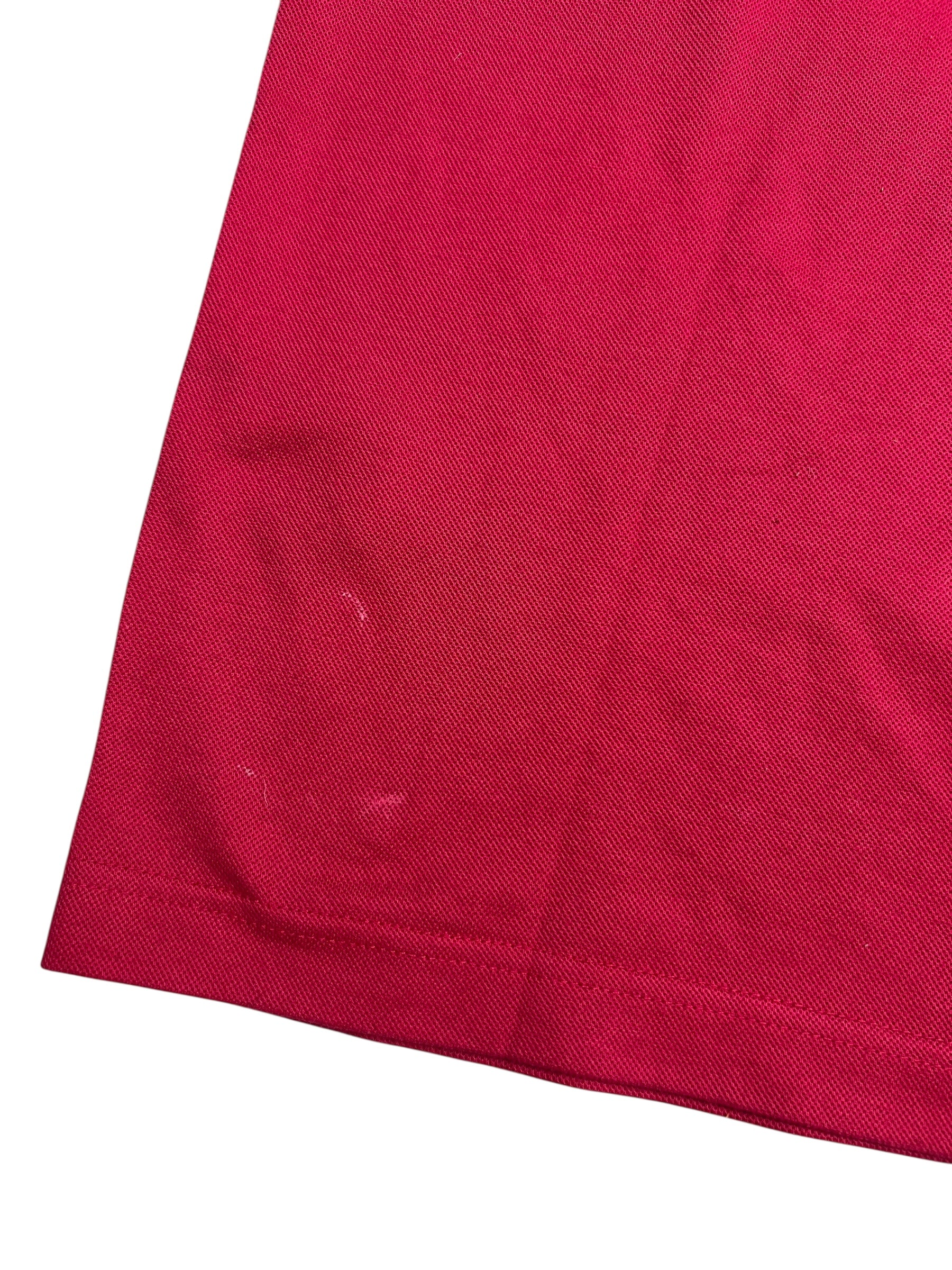 Nahaufnahme der unteren Ecke eines roten Burberry Polo Shirts (L) von ZAZA resell, die einen schwachen Lichtfleck in der Nähe des Saums zeigt. Zustand: 8/10.