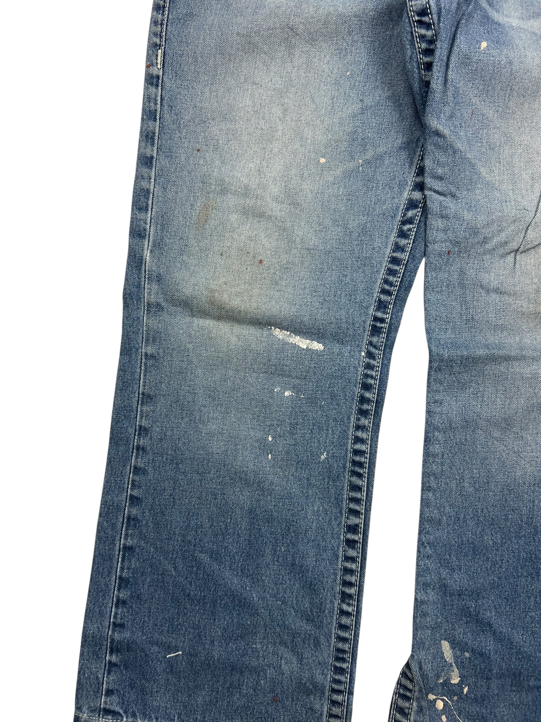 True Religion Straight | 34 (L) von ZAZA resell: verblasste blaue Jeans mit Farbflecken und Abnutzungserscheinungen an den Beinen, sichtbaren Falten und Verfärbungen für einen getragenen Look. Abgebildet vor einem weißen Hintergrund; Bundweite sorgt für eine bequeme Passform.