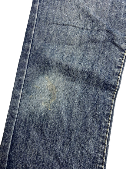 Eine Nahaufnahme der Apple Bottoms Mid Rise Boot Jeans von ZAZA resell zeigt verblichenen, abgenutzten blauen Denim in der Nähe des Knies, mit sichtbaren Nähten und Stoffdetails.